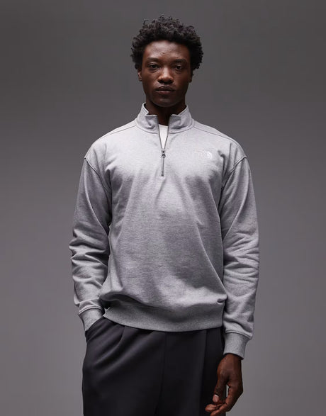 Man wearing a gray quarter-zip sweatshirt against a gray background